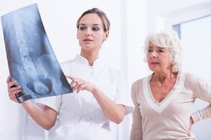 лекарят показва пациентка рентгенова снимка на гръбнака